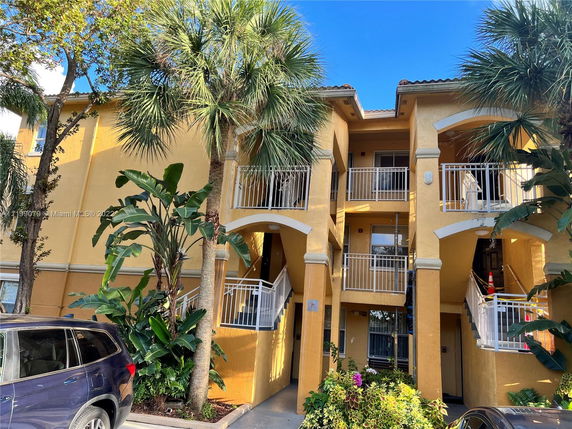 Front view of a multi-story building with balconies and a yellow exterior.