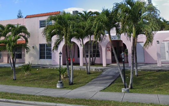 Front view of a two-story house with pink walls and arched windows.