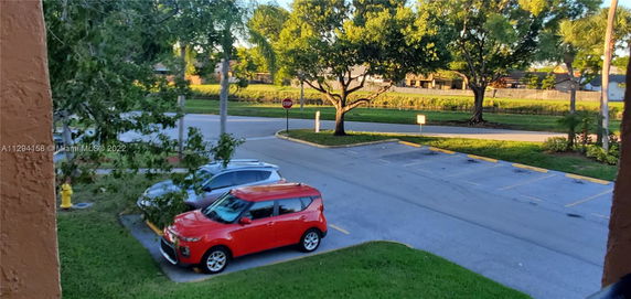 View of an outdoor parking area with cars parked and a road nearby.