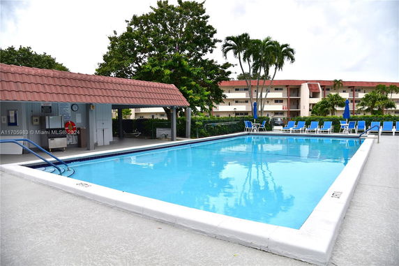 Outdoor swimming pool with lounge chairs and a covered area.