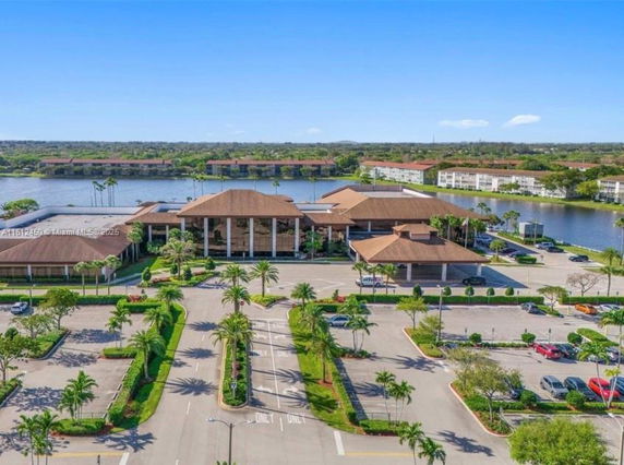 Aerial view of a large complex with multiple buildings, surrounded by water bodies and landscaped parking areas.