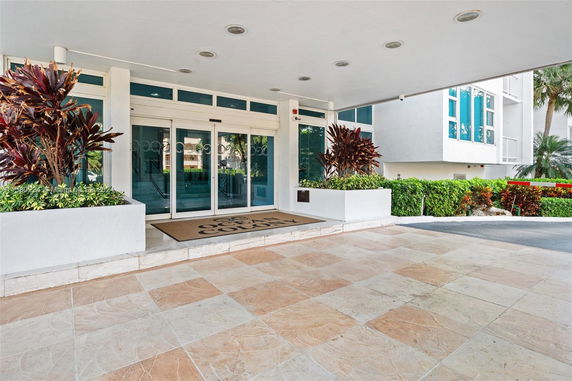 Entrance view of a building with sliding glass doors and potted plants.