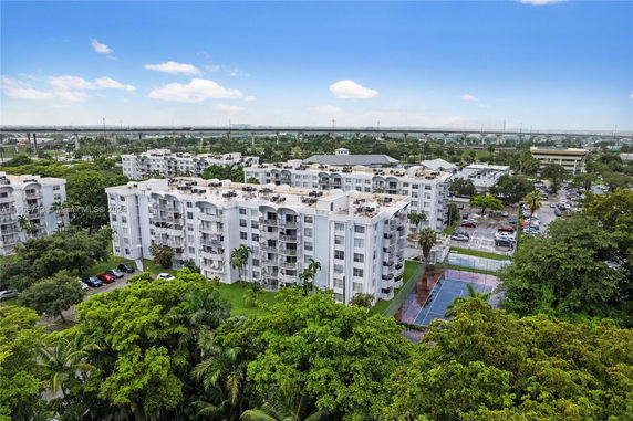 Aerial view of apartment buildings with trees and parking lots surrounding them.