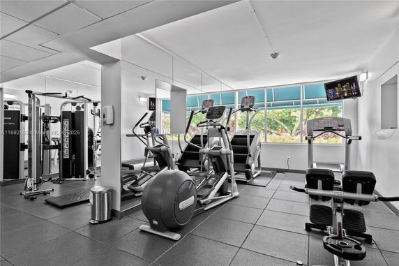Interior view of a modern gym with exercise equipment and large windows.