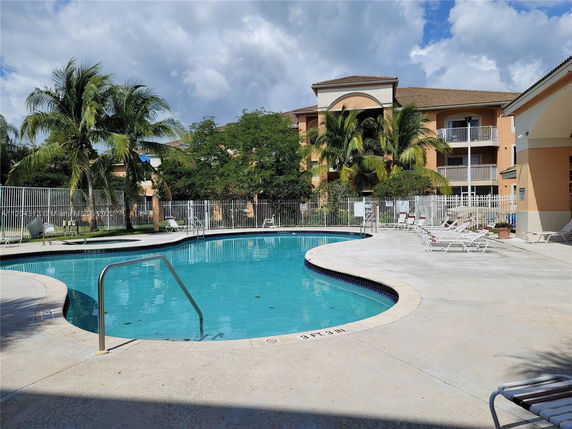 Outdoor swimming pool with lounge chairs and a building in the background.