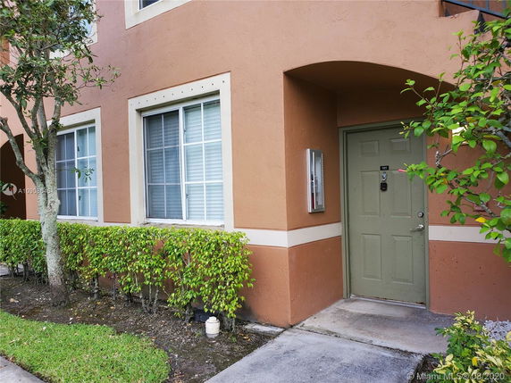 Front view of the entrance to a multi-story building with windows and a green door labeled 101.
