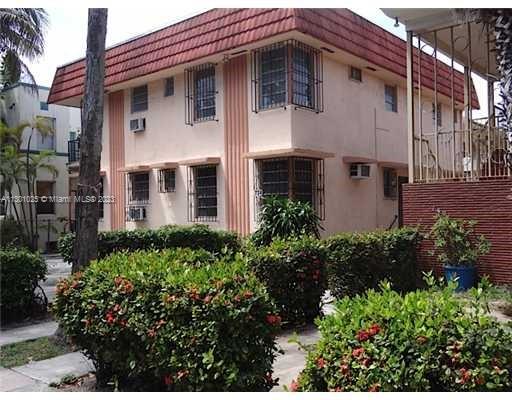 Front view of a two-story house with a red-tiled roof and barred windows.