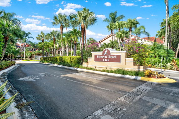 Entrance view of Biscayne Beach Club with palm trees and signage.