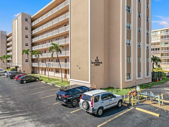 Front view of a multi-story residential building with balconies and parking area.