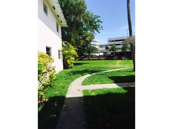 View of a grassy area with paved walkways beside a building.