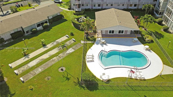 Aerial view of a residential area featuring a house with a swimming pool and surrounding lawn.
