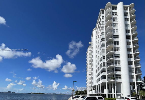 Front view of a multi-story waterfront building with balconies.