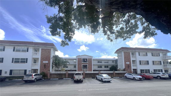 Front view of a multi-story residential building with parking area in front.