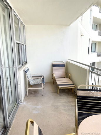 View of a small apartment balcony with chairs and a table.