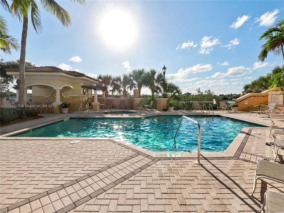 Outdoor pool area with a small pavilion and palm trees.