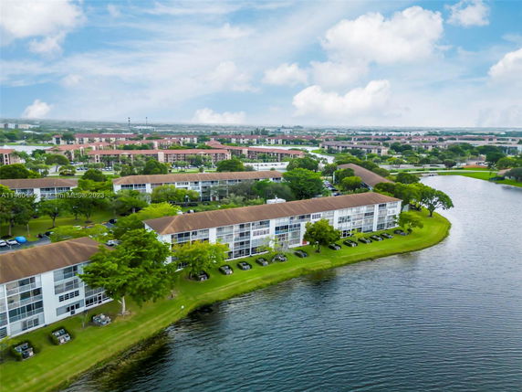 Aerial view of residential buildings near a lake with surrounding greenery.