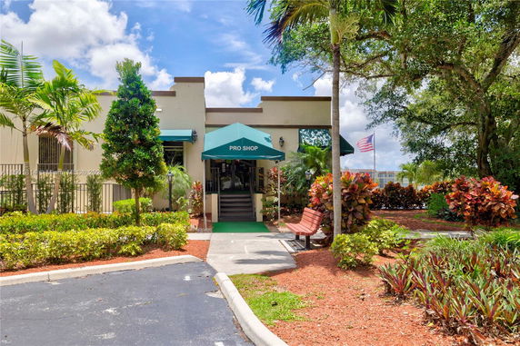 Front view of a pro shop with a green awning and landscaped surroundings.