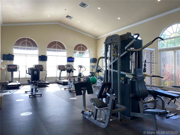 Interior view of a gym with exercise equipment and large windows.