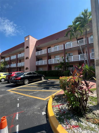 Front view of a multi-story building with balconies and parking area.