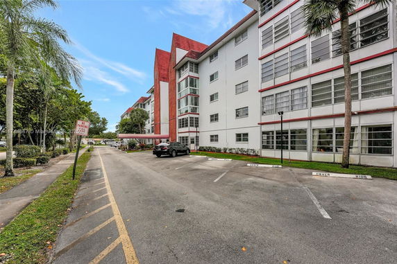 Outdoor parking area next to a multi-story building with red and white exterior.