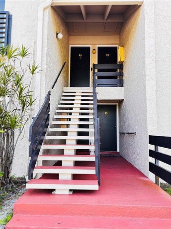 Front view of a building entrance with a red painted staircase and two doors labeled G and H.