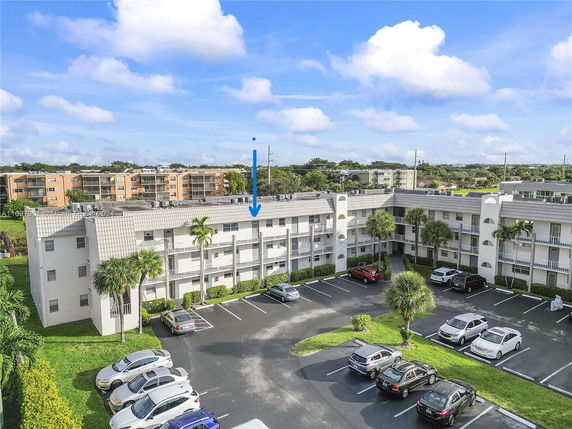 Front view of a multi-story apartment building with parking area in front.