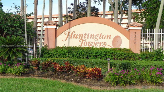 Front view of Huntington Towers with a decorative sign and landscaped garden.