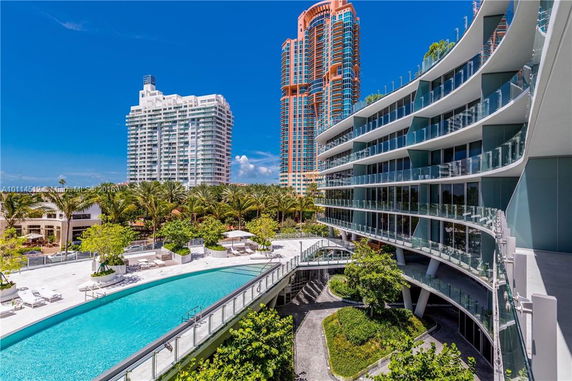 Outdoor view of a swimming pool next to a modern multi-story building with curved balconies.