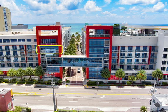Front view of a modern multi-story building with a connecting glass bridge.