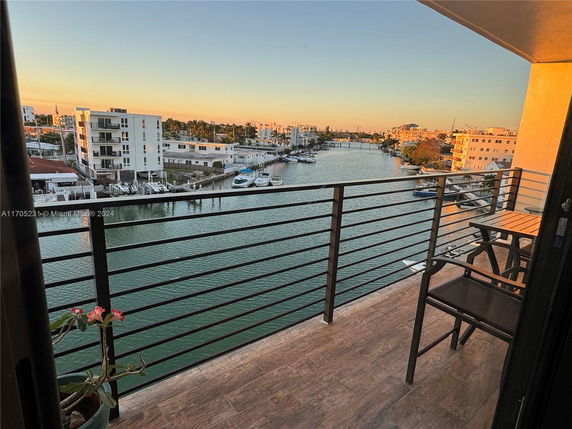 Panoramic view of waterfront buildings from a balcony at sunset.