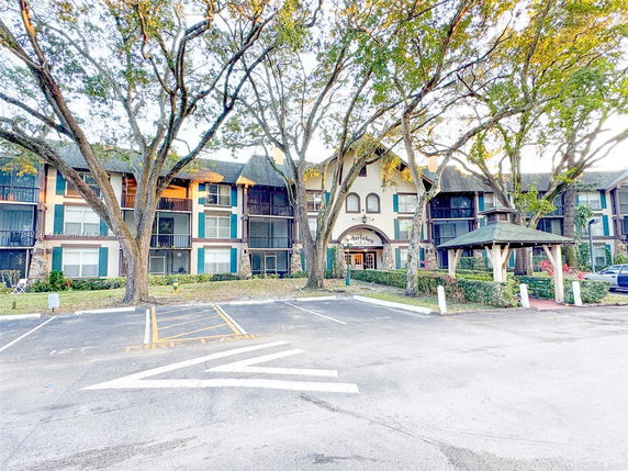 Front view of a multi-story residential building with balconies and a landscaped entrance.