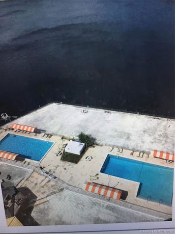 Rooftop area with two swimming pools and several orange and white striped canopies.