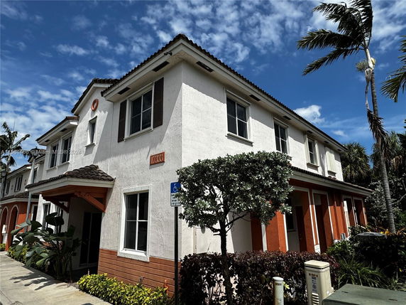 Front view of a two-story townhouse with a tiled roof and multiple windows.