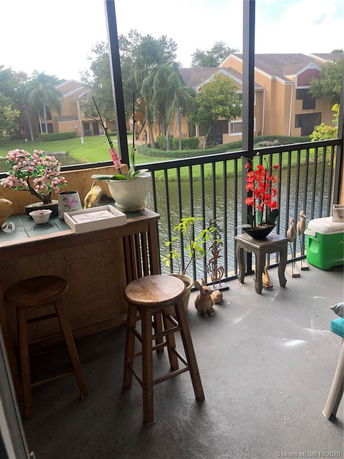 Balcony view overlooking a pond and other buildings with trees around.