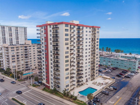 Front view of a multi-story apartment building with balconies, located near the ocean.