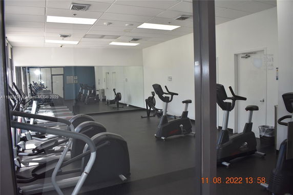 Interior view of a gym with exercise machines and mirrored walls.