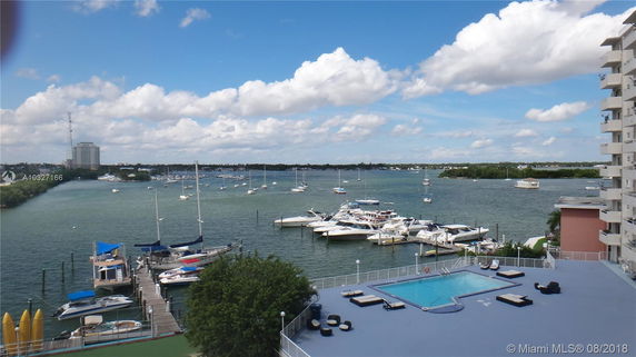 Wide angle view overlooking a waterfront area with boats and a swimming pool in the foreground.
