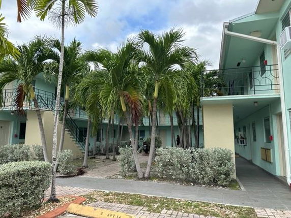 Front view of a two-story building with balconies and outdoor stairs.