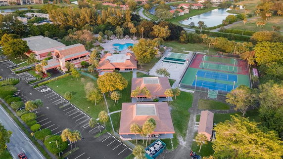 Aerial view of a recreational complex with parking areas, tennis courts, and a swimming pool.