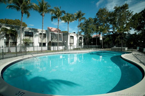 Outdoor swimming pool with adjacent buildings and palm trees.