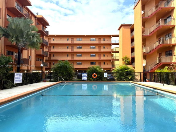 Outdoor swimming pool with multi-story building in the background.