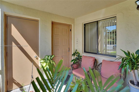 Front porch view of a house entrance with double doors and seating area.