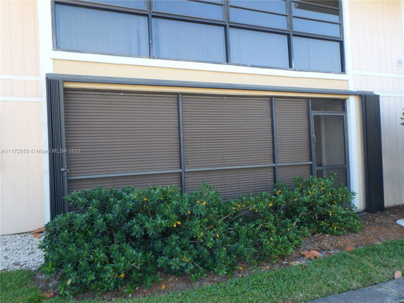 Front view of a building with large windows and metal shutters.