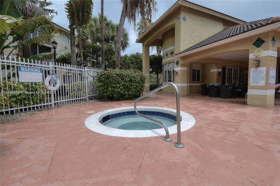 Outdoor area with a small circular hot tub and a building with a tiled roof.