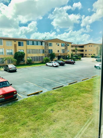 Outdoor parking area with cars in front of a multi-story building.