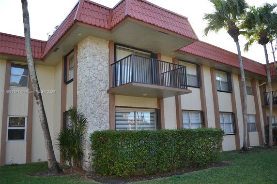 Front view of a two-story building with a balcony and textured stone wall accents.