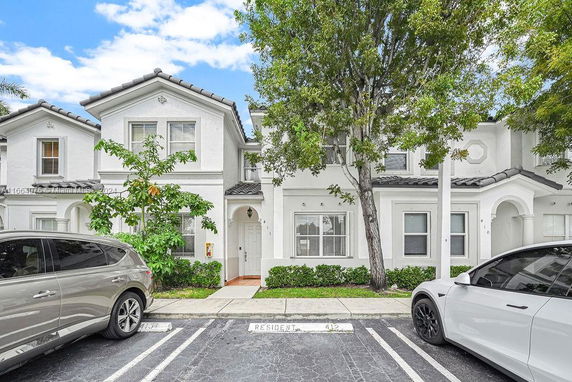 Front view of a two-story townhouse with a white facade and arched entryway.