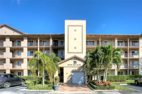 Front view of a multi-story residential building with balconies and a central entrance.