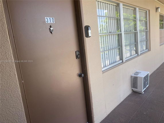 Front view of an apartment unit door with a number plate and adjacent windows.