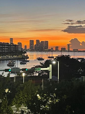 Wide-angle view of a city skyline at sunset with boats in the foreground.